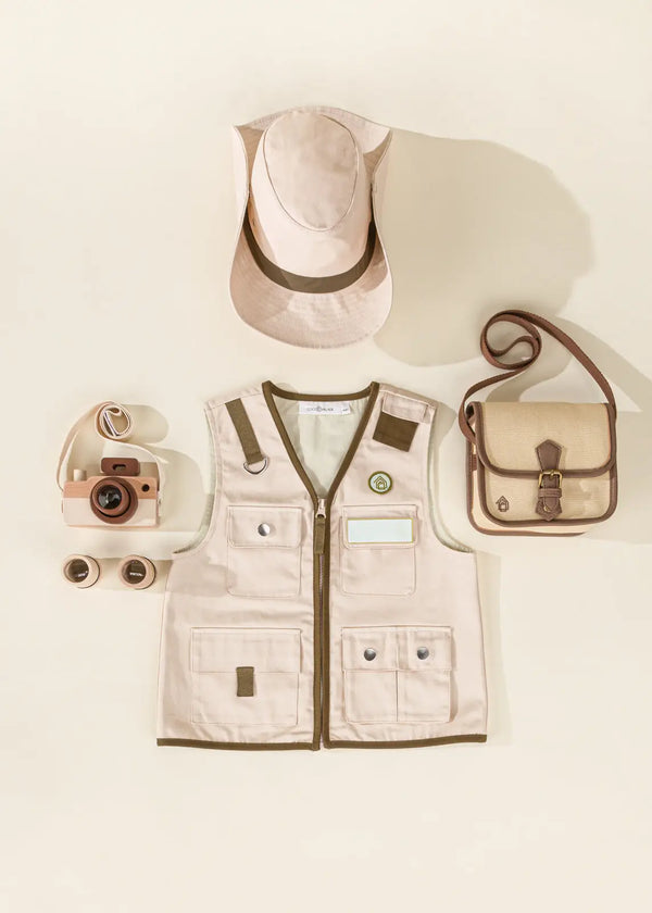 Flat lay of Explorer Dress-Up Costume including a beige vest, matching hat, camera, sunglasses, and crossbody bag, arranged on a light background.
