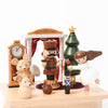 A festive display featuring a Nutcracker Ballet Music Box made from sustainably sourced wood, an angel, a small teddy bear, and other whimsical figures around a miniature clock and tree, set against a