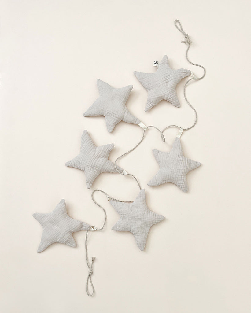 Six Handmade Star Garlands connected by a string, arranged in a cascading pattern on a light background. This neutral color garland is made of organic cotton.