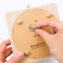 A person's hands tuning a Gorilla Music Box made from sustainably sourced wood, engraved with the word "wonderful." The box is round, with visible metallic components and pegs.