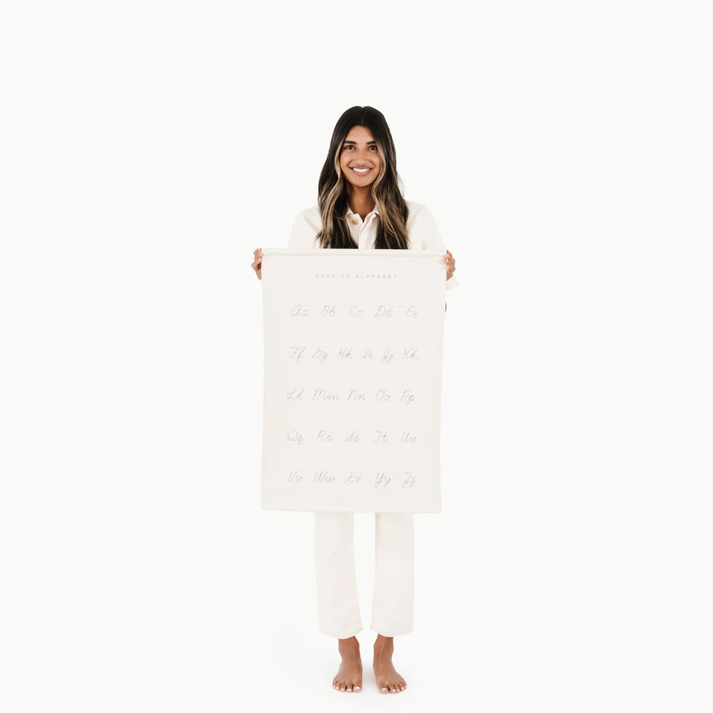 A cheerful woman with long hair, wearing a white outfit, standing and holding a large Gathre Cursive Poster in front of her, isolated on a white background.