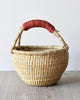 A woven basket with a dark red leather handle.