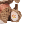 Close-up of an Olli Ella Dinkum Dog's foot with a stitched rainbow paw print on a white pad, set against a striped black and white background featuring a magnetic bone accessory.