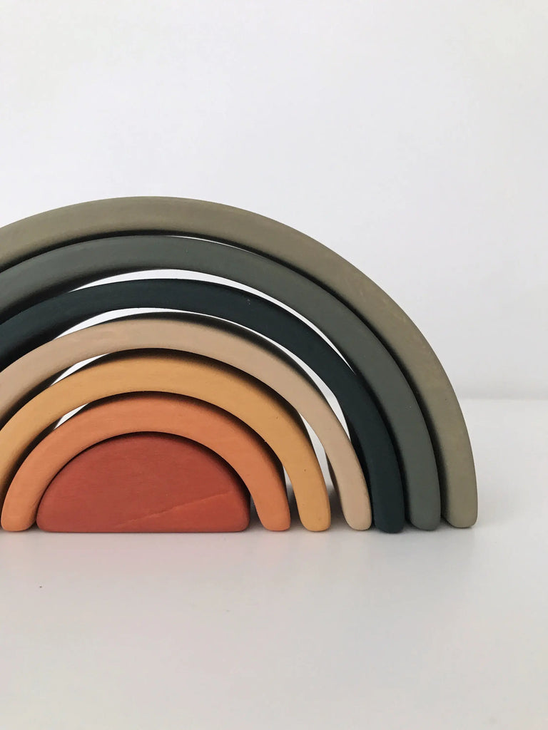A Handmade Mini Rainbow Stacker - Jungle consisting of six arches in shades of grey, silver, and orange, arranged in size order to form a stacking toy rainbow shape against a white background.