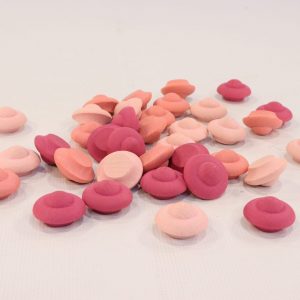 A collection of Grapat Mandala Flower-shaped candies in shades of pink, peach, and white, scattered on a light background with sustainable forests.
