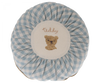 A round Maileg Cushion, Small with a blue and white checkered border, featuring an embroidered brown teddy bear and the word "teddy" in the center.