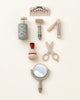 An array of Pretend Play Wooden Barber Set neatly arranged on a light background, including a shaving brush, razor, after-shave bottle, a comb, tweezers, nail clippers, scissors, and a hand