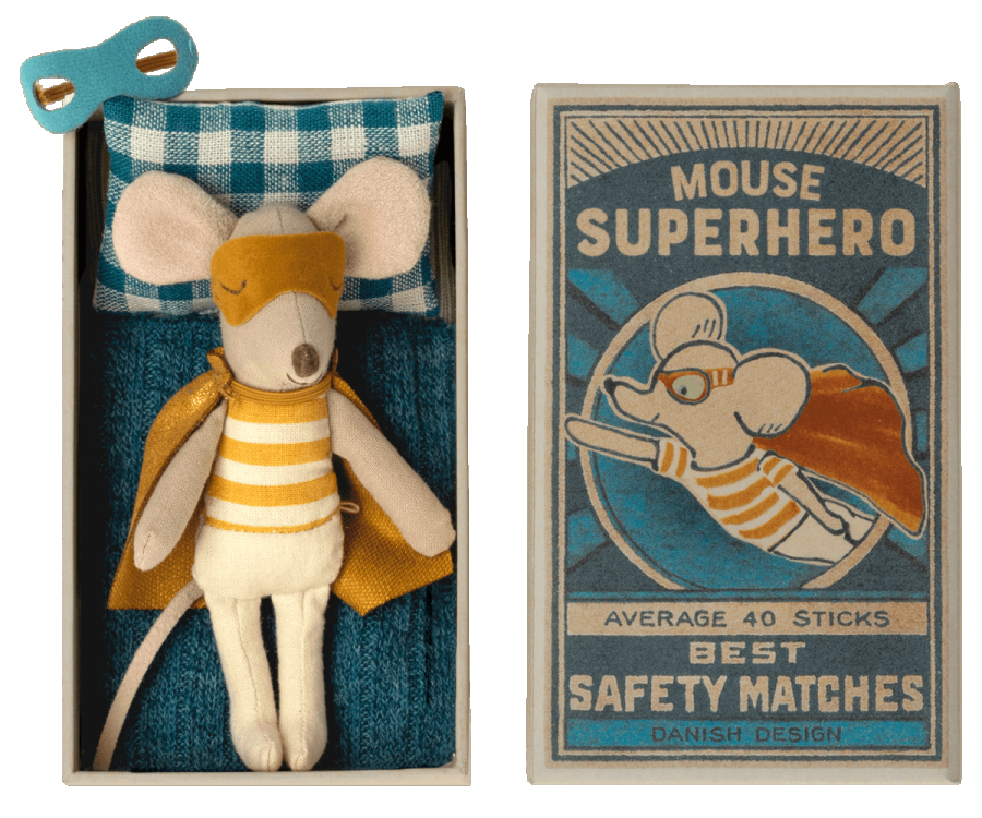 A Maileg | Superhero Mouse, Little Brother dressed as a superhero, lying in a colorful matchbox labeled "Little Brother Superhero" with comic book-style artwork, all suggesting a Danish design theme.