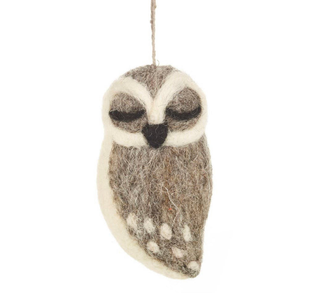 A Grey Colored Handmade Felt Owl Ornament, primarily in shades of gray and white, hangs against a plain white background. Its design features distinct, large black and white eyes and was crafted in Nepal.