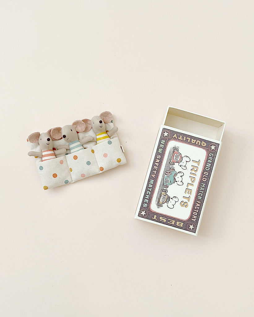 A box of Maileg | Triplets Baby Mice In Matchbox designed to look like a circus tent, with several matches on top shaped like baby mice against a polka-dotted background.