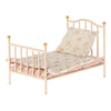 A Maileg Miniature Bed in pink with gold accents, designed for Maileg friends, featuring ornate details and dressed with a floral-patterned mattress and pillow.