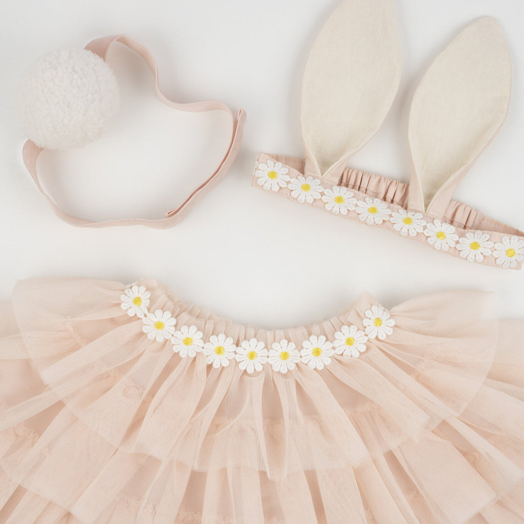 Flat lay image of a Meri Meri Peach Tulle Bunny Costume including a pink tutu with daisy decorations, bunny ears headband, and a bunny tail on a white background.