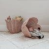 Two Olli Ella Rattan Lily Basket Sets shaped like whales on a soft rug, one open containing plush animals including a zebra, creating a cozy, playful atmosphere in a child's room.