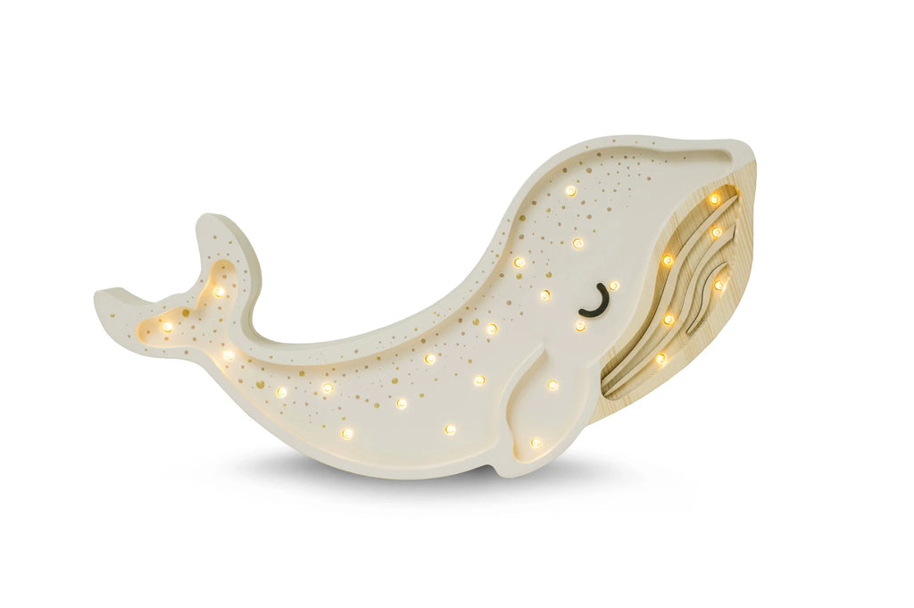 A decorative Little Lights Whale Lamp with a smiling face, glittering body, and internal lighting that glows through star-shaped cutouts, crafted from natural pinewood, isolated on a white background.