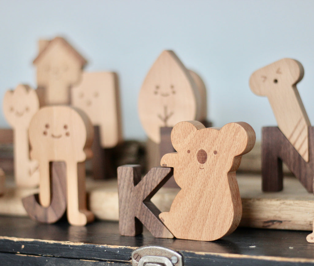 Close-up of the Ultimate Wooden Alphabet Puzzle including a koala, bear, and other animal-shaped letters on a shelf, showcasing playful, educational toys with a focus on natural textures.