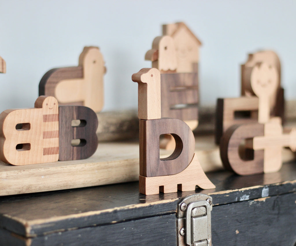 Ultimate Wooden Alphabet Puzzle shaped like animals on a table, featuring letters a, b, d, and g, artistically crafted with parts of the animals forming elements of each letter.
