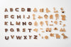 Ultimate Wooden Alphabet Puzzle from a to z arranged in rows on a white background, accompanied by various cute animal and object shapes like a bear, house, and truck.