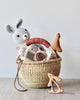 A woven basket with a leather handle, stuffed with various toys.