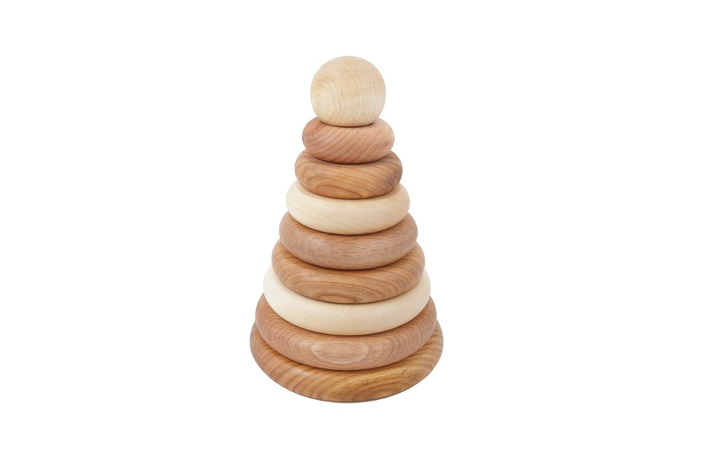 A wooden stacking toy with wooden rings in various natural shade of wood, stacked from large to small, topped with a sphere shaped wooden piece.