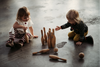 Children sitting on the floor playing with wooden bowling set. 