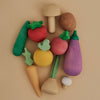 The Raduga Grez Handmade Wooden Vegetable Set features a vibrant array of colorful vegetables, including a carrot, mushroom, tomato, and eggplant. Expertly handcrafted and skillfully arranged on a neutral background, these wooden toys infuse any setting with playful delight.