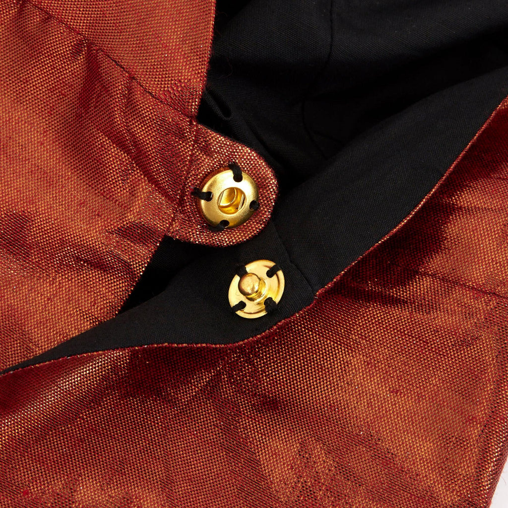 Close-up view of a Meri Meri Dinosaur Costume with two round, golden buttons fastened on a black fabric area, showing detailed button design and stitching.