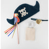 Meri Meri Pirate Costume accessories arranged on a white background, including a blue pirate hat with a skull and crossbones, a colorful parrot, a gold-colored eye patch, a beige pouch, and more.