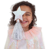 A young girl with curly hair, smiling with her eyes closed, wearing a Meri Meri Iridescent Sequin Cape Costume and holding a glittery star in front of her face.